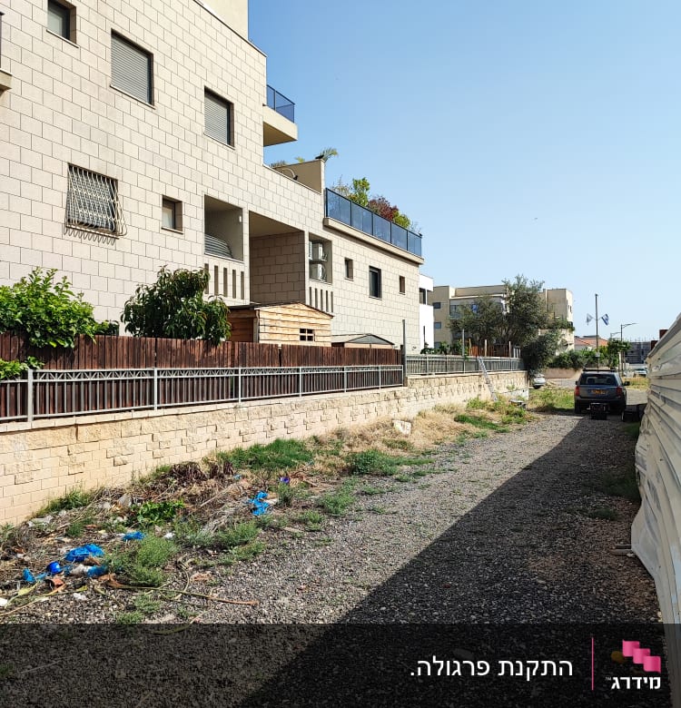 שביל חצץ עם גדר עץ וצמחייה בצד